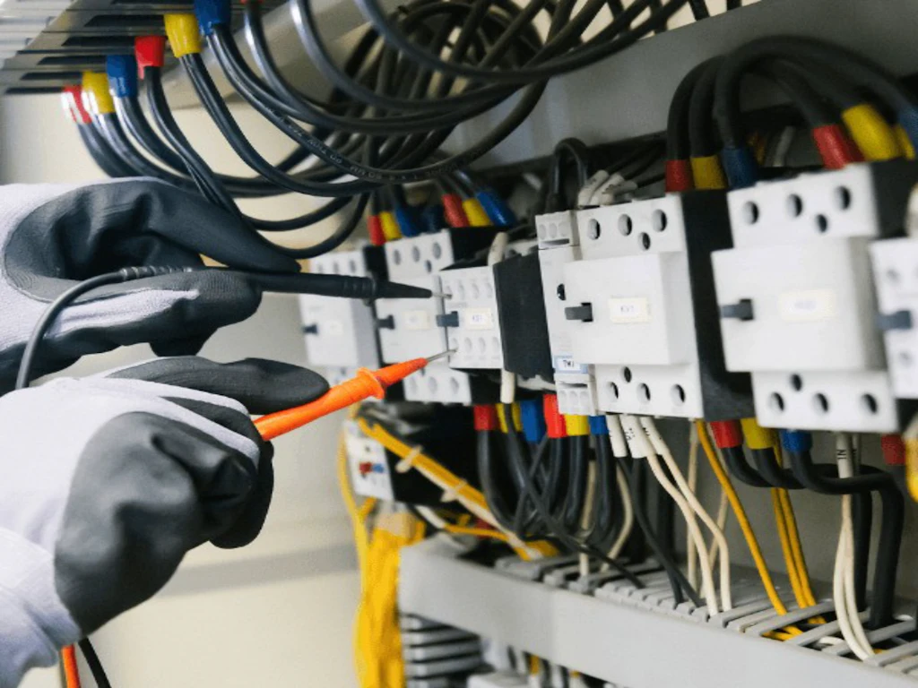 Tecnico che verifica un quadro elettrico con un multimetro